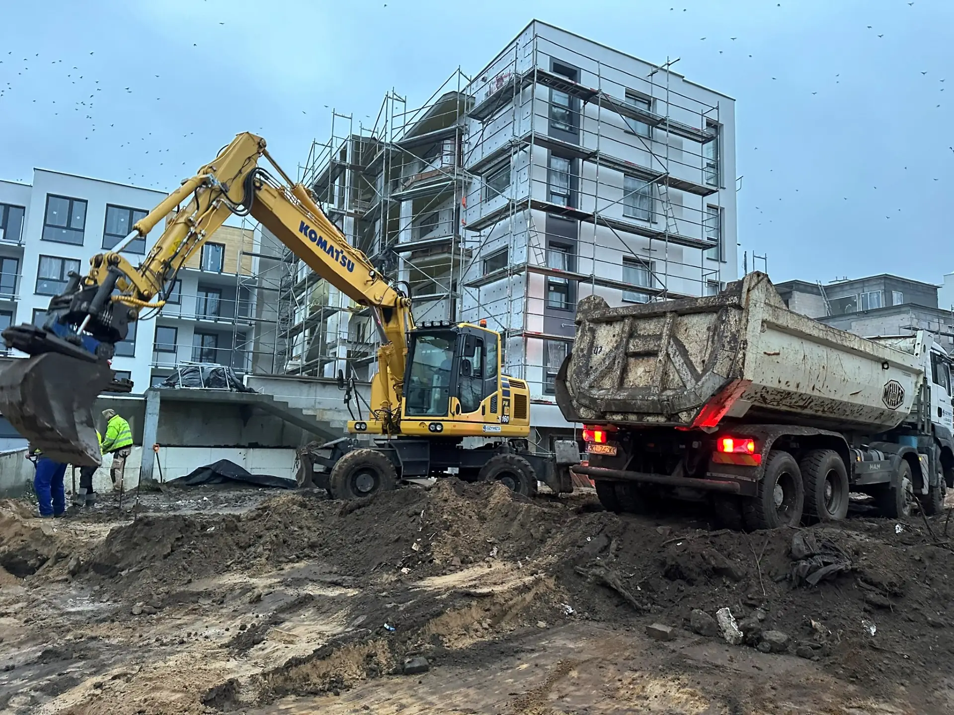 Koparka Komatsu PW 160 firmy SZYMETA ładuje ziemię na wywrotkę MAN na budowie osiedla w Kołobrzegu
