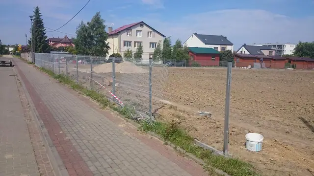 Gotowe ogrodzenie na stalowych słupkach wzdłuż chodnika z czerwonej kostki w Ustroniu Morskim