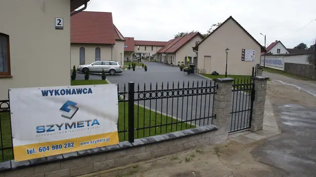 Rozległy wybrukowany plac przed budynkiem Domu Pielgrzyma w Skrzatuszu