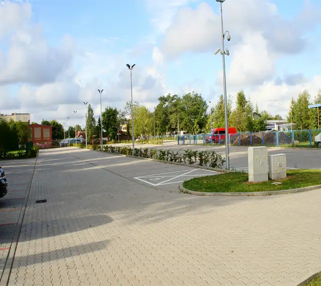 Parking z kostki brukowej z wydzielonym miejscem dla niepełnosprawnych przy kompleksie stadionów